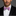Man wearing a black suit with a white shirt and pink bow tie against a gray background