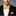 Man wearing a black suit with a yellow and blue polka bow tie and pocket square on a gray background