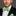 Man wearing a black suit with a green polka dot bow tie and pocket square on a gray background