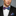 Man wearing a black suit with a colorful bow tie and pocket square on a gray background