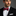 Man wearing a black suit with a red and blue striped bow tie on a gray background