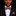 Man wearing a black suit with a red and blue paisley bow tie and pocket square on a black background