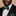 Man wearing a black suit with a blue paisley bow tie and pocket square against a beige background