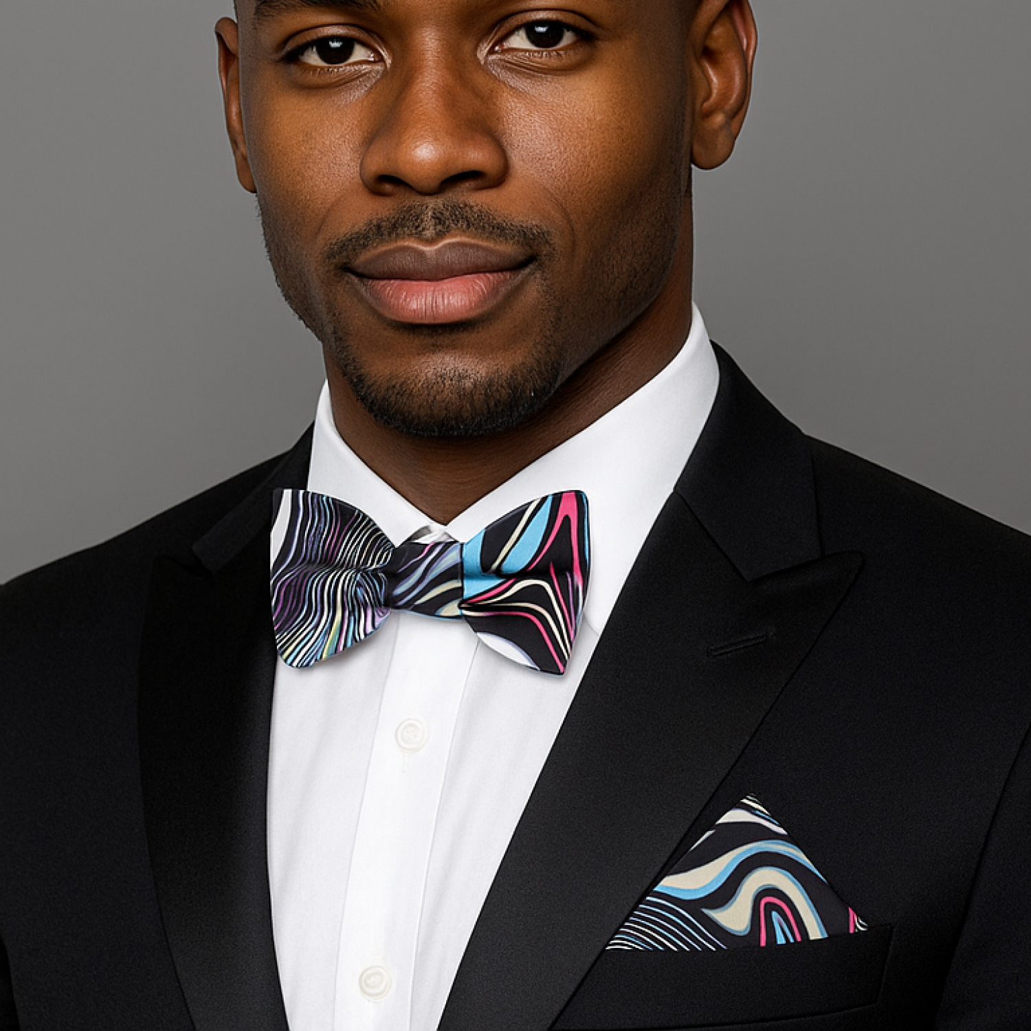 Man wearing black suit with multi colored abstract bow tie and matching square