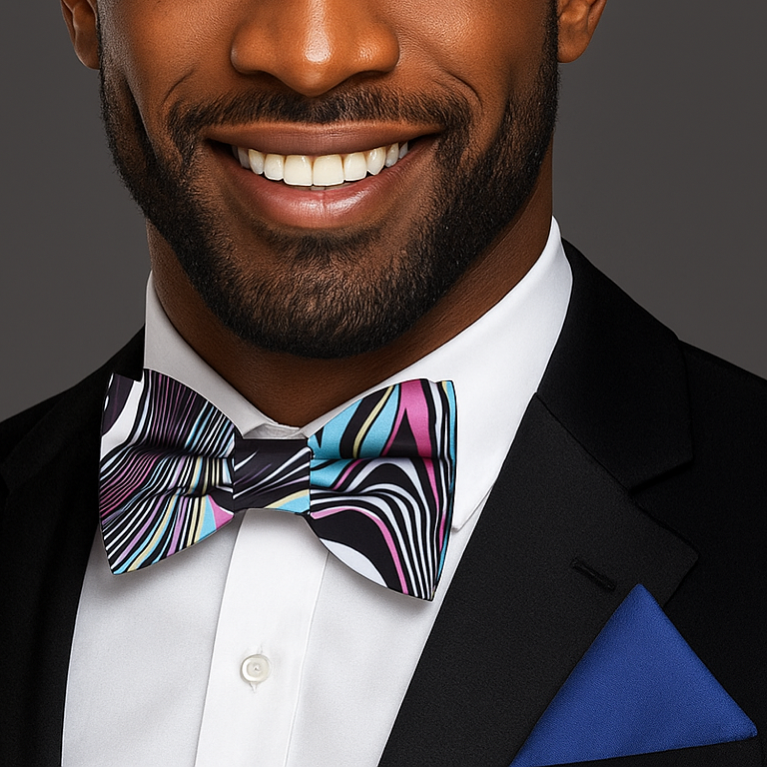 Man wearing black suit with multi colored abstract bow tie and blue square