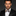 Man wearing a black suit with a patterned bow tie against a dark background