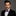 Man wearing a black suit with a white shirt and purple paisley bow tie against a gray background
