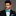 Man wearing a black suit with a blue bow tie and pocket square on a gray background