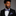 Man wearing a black suit with a colorful bow tie and pocket square on a gray background