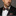 Man wearing a black suit with a colorful bow tie and pocket square against a gray background