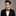 Man wearing a black suit with a colorful bow tie and pocket square against a gray background