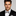 Man wearing a black tuxedo with a silver and black geometric patterned bow tie against a gray background