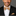 Man wearing a black suit with a beige bow tie and pocket square on a gray background
