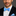 Man wearing a black suit with a blue bow tie and pocket square on a gray background