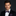 Man wearing a black suit with a patterned bow tie and pocket square on a dark background