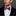 Man wearing a black suit with a colorful blue and pink waves bow tie and accenting blue and white dot square and white shirt against a gray background