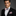Man wearing a black suit with a pink bow tie and pocket square on a gray background