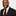 Man wearing a black suit with a red striped tie and pocket square on a white background