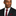 Man wearing a black suit with a red striped thin tie and pocket square on a white background