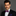 Man wearing a black suit with a colorful blue and pink paisley bow tie against a gray background