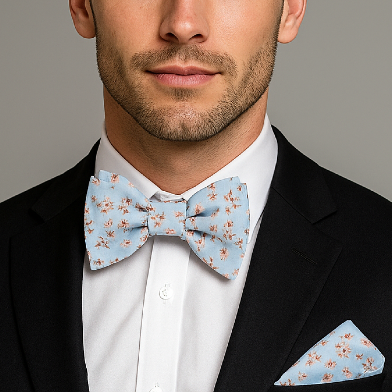 Man wearing a black suit with a white shirt and Light Blue, Burgundy, Cream Magnolia Flowers Bow Tie And Pocket Square