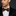 Man wearing a black suit with a white shirt and leopard print bow tie on a dark background
