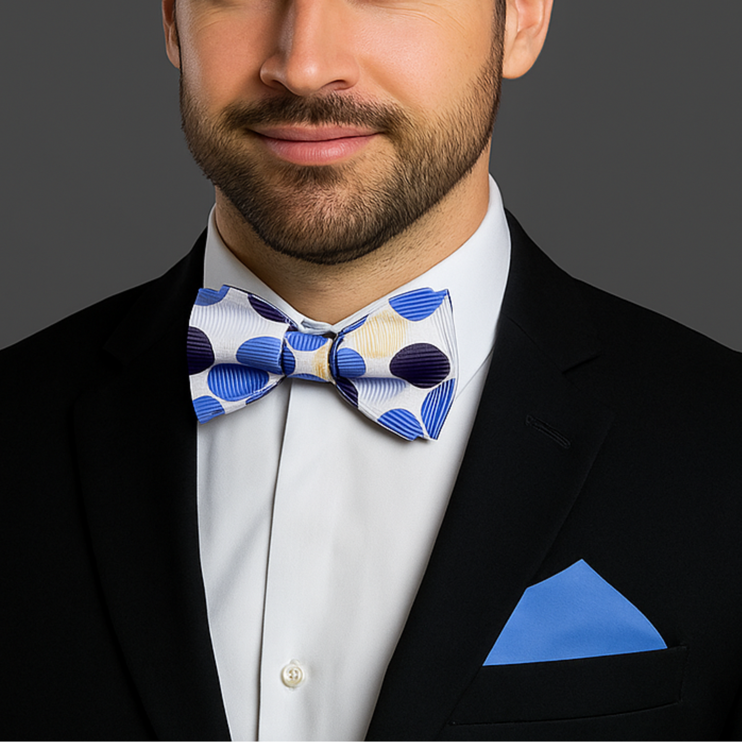 Man wearing a black suit with a White, Blue Polka Dot Bow Tie and Blue Square