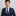 Man wearing a navy suit with a pink paisley tie and pocket square on a gray background