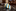 Striped tie with blue, yellow, and white pattern on a wooden surface with a blurred natural background