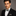 Man wearing a black suit with a Green, Gold, Blue Stripe Bow Tie and Pocket Square against a gray background