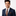 Man wearing a navy suit with a patterned tie and pocket square on a white background