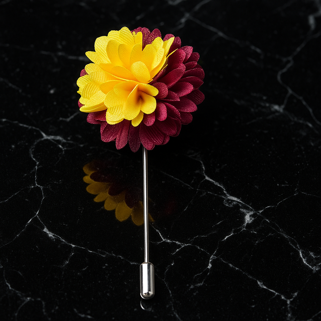 Floral lapel pin with yellow and red flowers on a black marble background