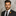 Man in a suit with a floral boutonniere against a marble wall