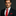 Man wearing a black suit with a red tie and pocket square on a dark background