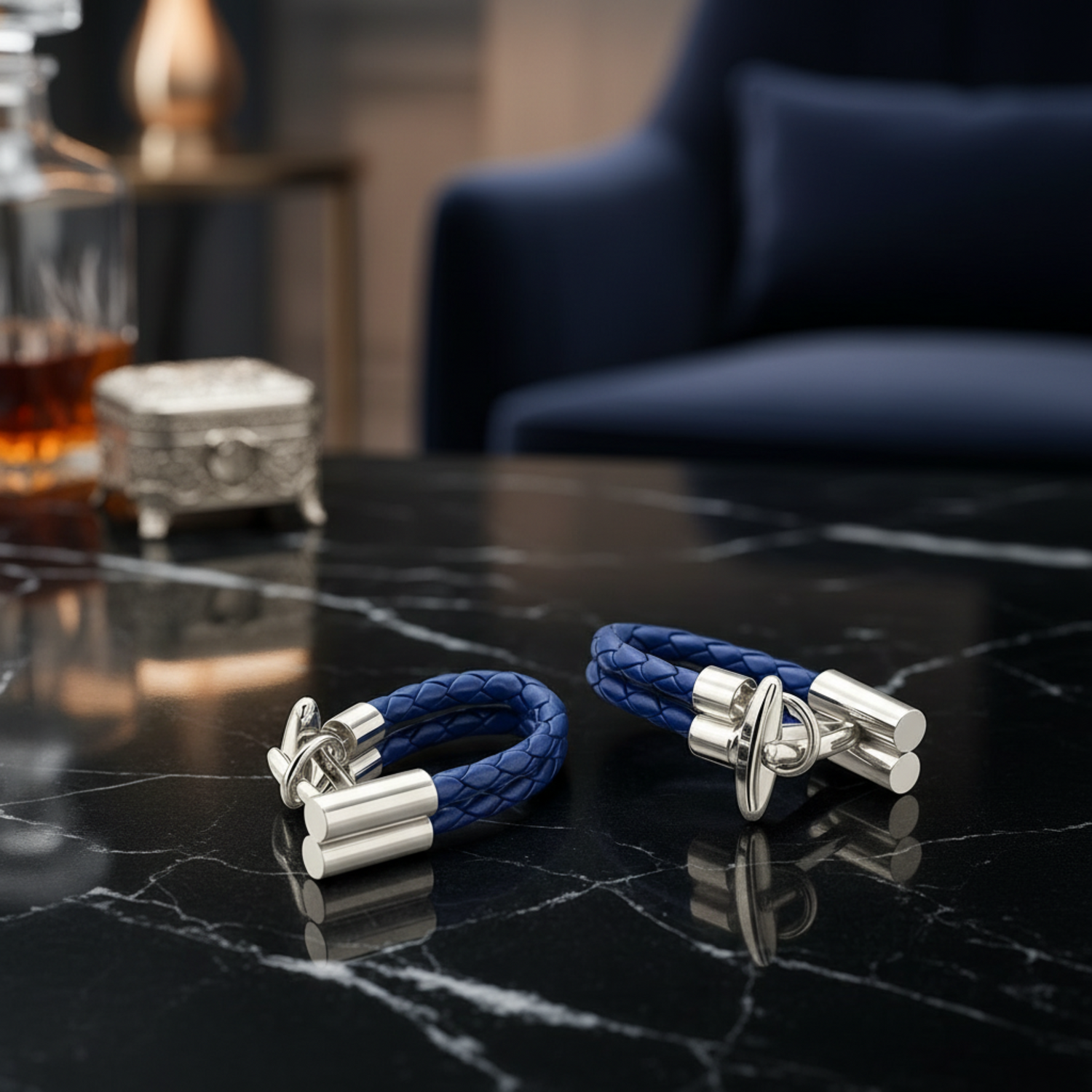 Pair of blue leather cufflinks with silver clasps on a dark marble surface