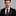 Man wearing a black suit with a red tie and pocket square on a gray background