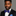 Man wearing a black suit with a blue bow tie and pocket square on a gray background
