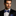 Man wearing a black suit with a Blue, Light Blue, Black Color Fleck Camouflage Pattern Bow Tie, Pocket Square on a gray background