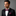Man wearing a black suit with a pink bow tie and matching pocket square on a gray background