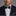 Man wearing a dark suit with a A Black, Grey Camo Fleck Pattern Self Tie Bow Tie, Matching Pocket Square against a gray background