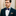 Man wearing a navy suit with a patterned bow tie and pocket square against a neutral background