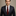 Man wearing a dark suit with a red tie against a neutral background