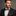 Man wearing a black suit with a patterned bow tie and pocket square on a gray background