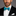 Man wearing a black suit with a white shirt and teal bow tie on a gray background