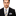 Man wearing a black suit with a striped tie and pocket square on a white background