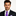 Man wearing a dark suit with a purple tie and matching pocket square on a white background