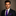 Man wearing a dark suit with a purple tie and pocket square against a neutral background