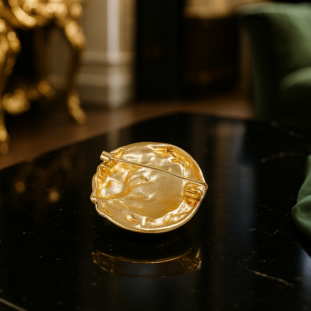 Gold brooch on a reflective surface with a blurred background