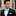 Man wearing a black suit with a white shirt and turquoise bow tie and pocket square.