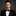 Man wearing a black tuxedo with a purple bow tie and pocket square on a gray background